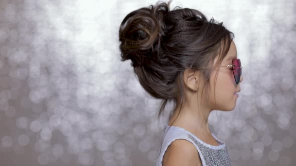 Cute Happy Little Girl Child in a Silver Dress Dancing on Background of Silver Bokeh.