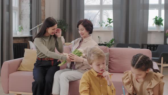 Adult Daughter Giving Flowers To Mother alt