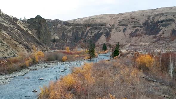 Ariel drone footage of a rugged river valley in fall. alt