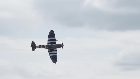 Slow motion of a D-Day Spitfire flying past the crowd during an air show. alt