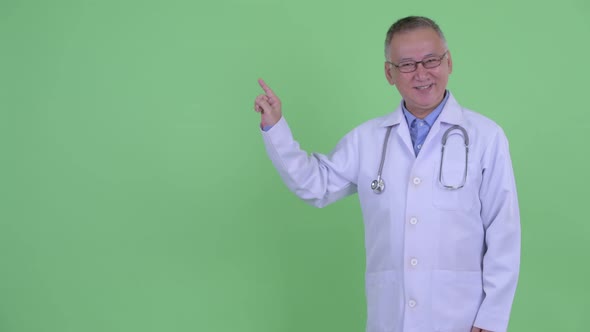 Happy Mature Japanese Man Doctor Talking and Touching Something alt
