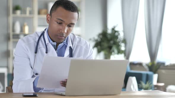 AfricanAmerican Doctor Reading Medical Report Diagnosing Patient alt