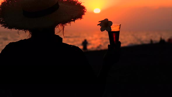 Woman on the Beach at Sunset Drinking a Cocktail alt