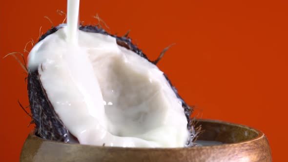 Dripping coconut water, drops of coconuts oil over red background, coconut milk pouring alt