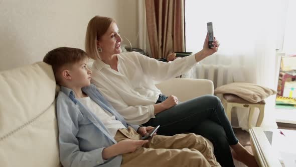 Boy and Adult Woman Take a Selfie on the Phone While Sitting on the Couch