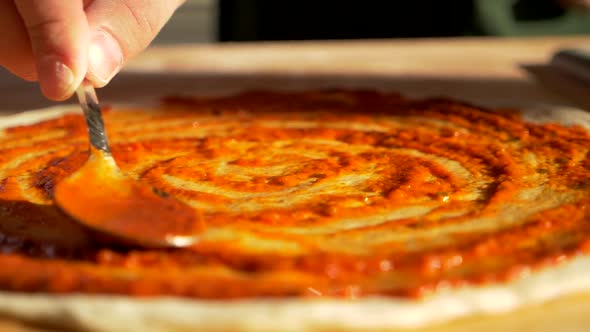 Tomato Sauce Gravy Spreading Filling with Spoon on Surface of Pizza Pie Dough