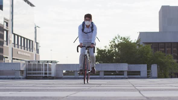 Asian man wearing face mask riding bicycle on the roof of corporate park alt