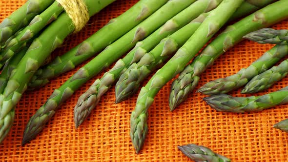 Fresh asparagus officinalis on orange background. Raw garden asparagus stems.	