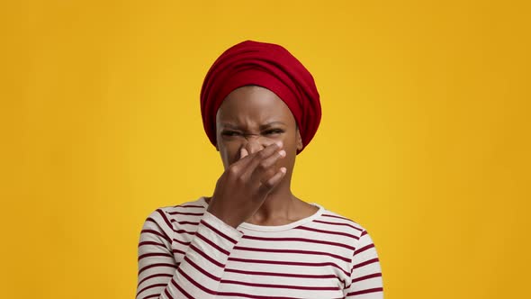 Disgusted Black Female Smelling Bad Stink Pinching Nose Yellow Background alt