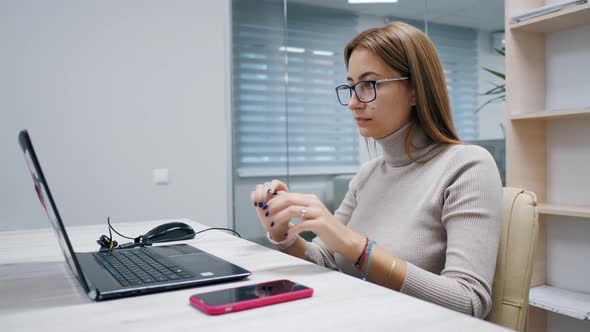 Cute Woman Working at a Laptop and Use Mobile Phone for Break Typing Text in the Office Female alt