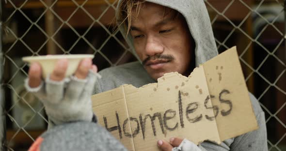 Homeless with dirty clothes holding homeless label alt
