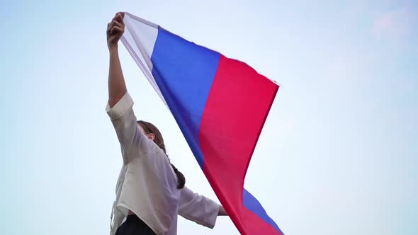Person with the Flag of Russia Stands and Washes Into the Distance. A Woman Patriot Looks Happily To