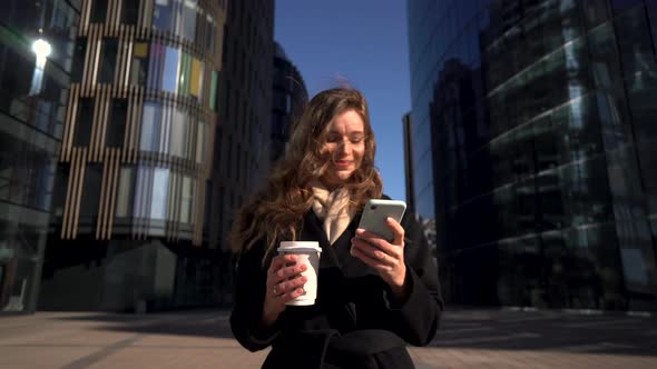 Young Business Woman With Coffee To Go Using Mobile Phone alt