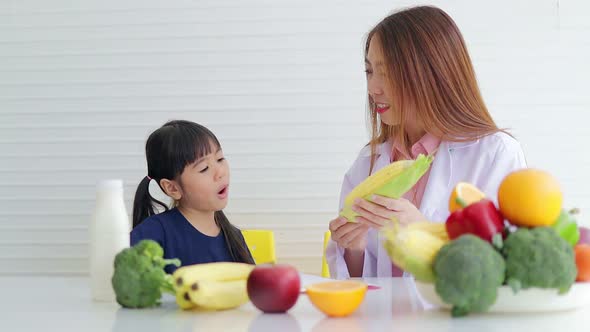 beautiful asian nutritionist Explain the benefits of food to a cute little girl. alt