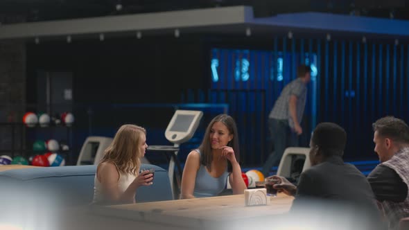 A Caucasian Brunette Man Knocks Out a Strike in a Bowling Alley and Runs Up to Her Friends to alt