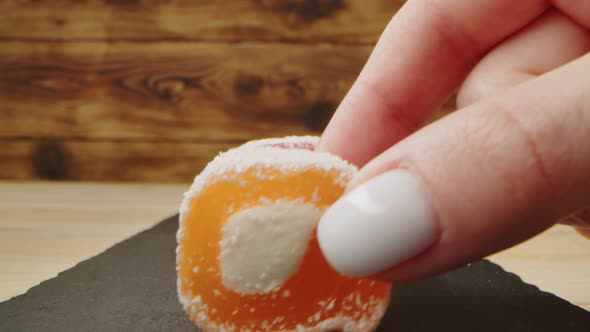 Hand Takes Eastern Sweets on Wooden Background Closeup