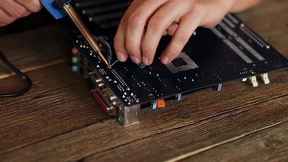 Engineer or Technician Repair Electronic Circuit Board with Soldering Iron. alt