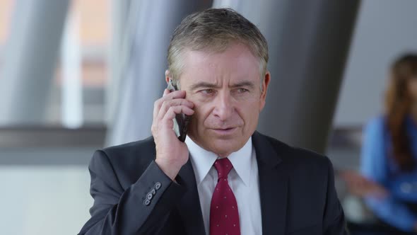 Mature businessman using cell phone in office lobby