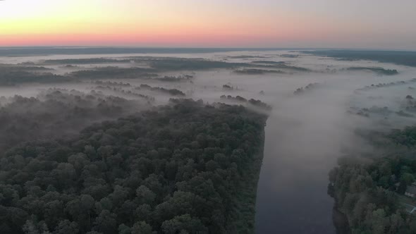 Aerial View of a Misty Winding River in the Middle of a Forest in a Remote Rural Area alt