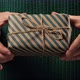 Girl  hand holding a gift wrapped in striped green-brown paper tied with a rope - VideoHive Item for Sale