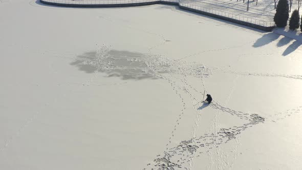Aerial Drone Shot Fisherman Is Fishing Alone on Frozen River alt