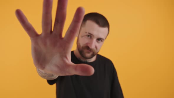 Young Bearded Attractive European Man Extanding an Opened Hand Towards the Camera Medium Closeup alt