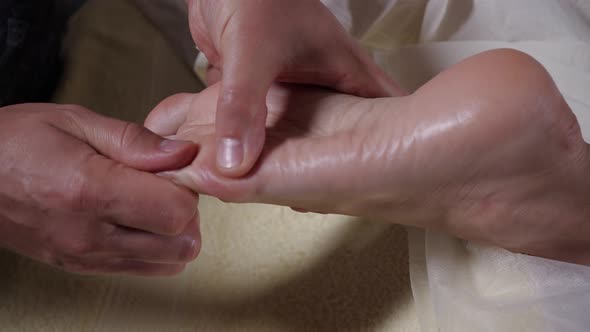 Specialist Does Foot Massage in Beauty Salon. Close-up View 