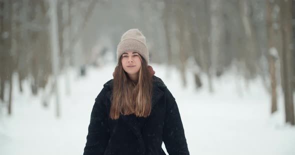 Attractive Young Beautiful Woman Walks in a Winter Snowy Forest and Smiling