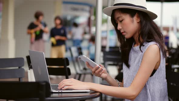 Young Asian woman using laptop working at a cafe in Thailand.