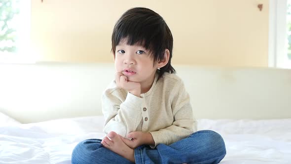 Unhappy Child Sitting On Bed alt