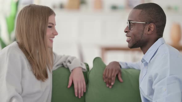 Attractive Mixed Race Couple Having Conversation While Sitting on Sofa alt