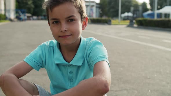 Cute Boy Sitting in Amusement Park. Close Up Relaxed Teen Boy Outside alt