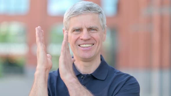 Outdoor Portrait of Successful Middle Aged Man Clapping with Hands alt