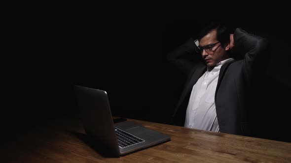 Tried and stressful businessman working late at night alone in dark room
