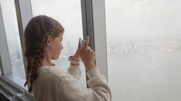Girl With Smartphone At Window In Skyscraper Filming New York City alt