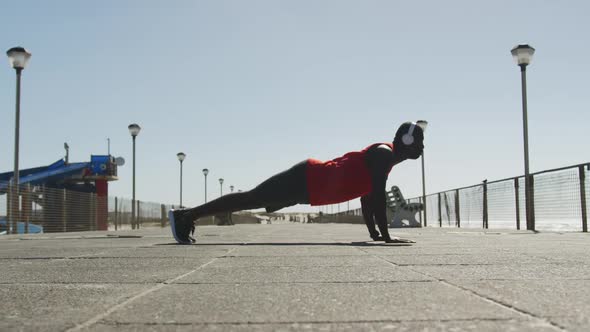 Focused african american man doing press ups, exercising outdoors by the seaside alt