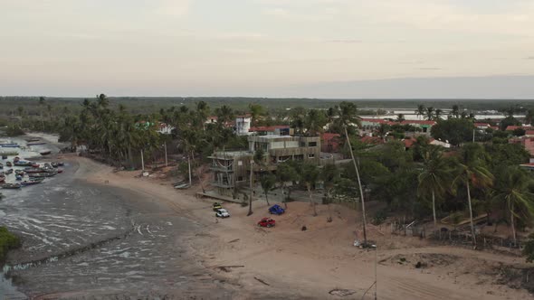 Crane flight toward beach buggy's by Brazil hotel resort on low tide beach alt