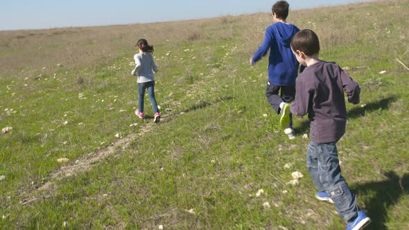Young kids running together on green hills outdoors in nature alt