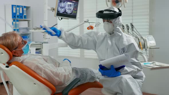 Nurse with Coverall Using Thermometer Before Examining Patient alt