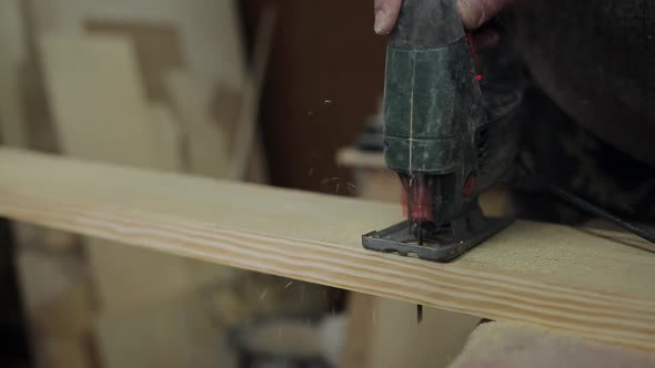 Man Sawing Boards on the Floor Electric Jigsaw