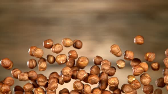 Super Slow Motion Shot of Flying Hazelnuts After Being Exploded on Wooden Background at 1000 Fps alt