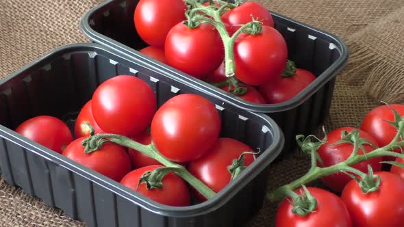 Cherry tomatoes in a plastic container on brown background