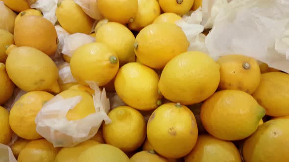 Pile of soft yellow lemons in a market, pan motion 