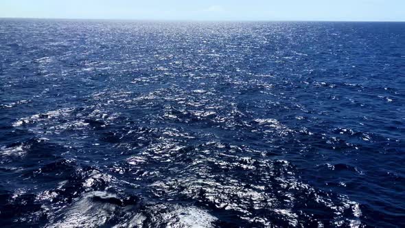 Wide view of the ocean waves as the sun reflects on the frothy rolling waters Segment 1 of 2 alt