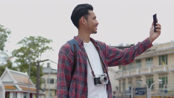 Asian man solo tourists standing using smartphones video chat with friends on the street.