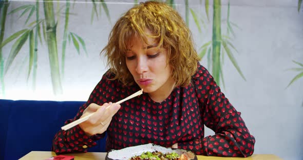 a Beautiful Bigeyed Young Woman in an Asian Bistro is Eating a Red Fish in Teriyaki Sauce with alt