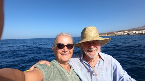 Beautiful and cute couple of seniors or old people in the middle of the sea driving and discovering alt