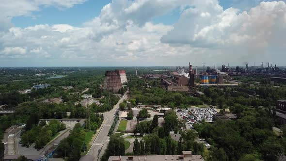 Blue sky with white clouds against the background of a steaming metallorgic plant. alt