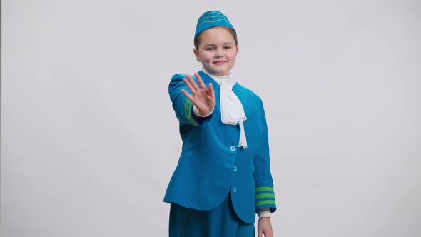 Front View of Little Stewardess Waving Looking at Camera Smiling Posing at White Background alt