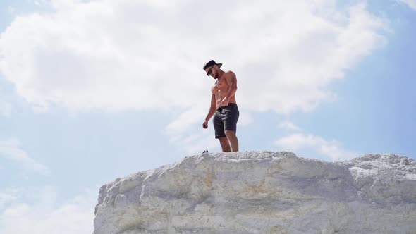 Shirtless athlete in cap and glasses on mountain. alt